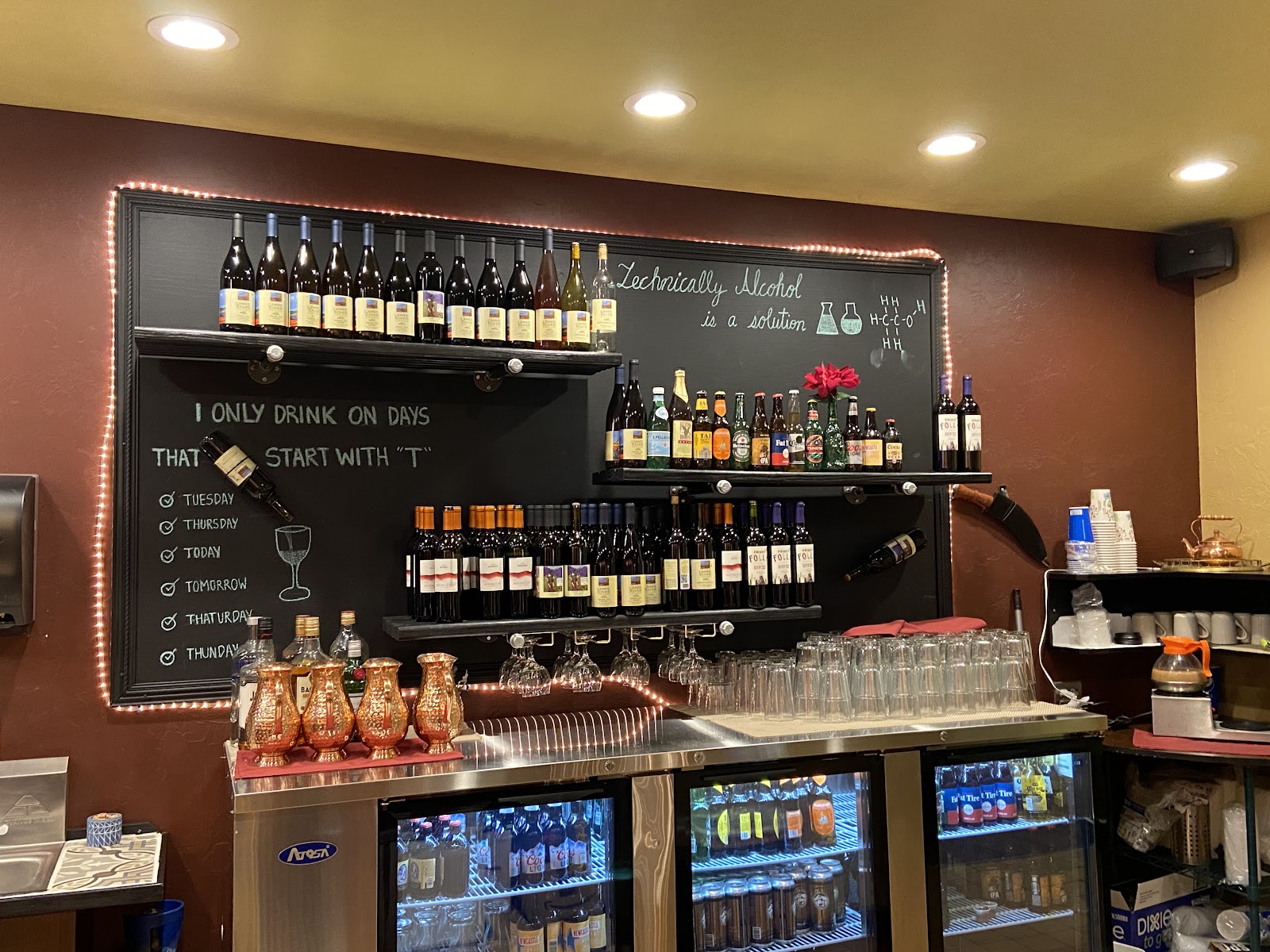 Karma Kitchen's bar wall: shelves of wine and beer around a hand-lettered chalkboard, copper mugs on the counter